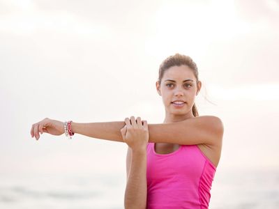Person stretching energetically outdoors at sunrise.